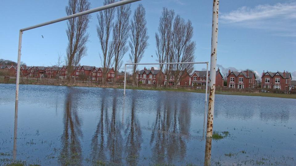 Waterlogged football pitch with goalposts standing in floodwater